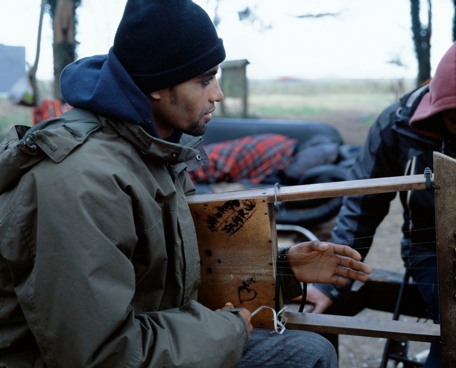 Bruno Serralongue, Jeune homme érythréen jouant de la musique, bois Chico Mendes, zone Marcel Doret, Calais, 8 février 2018. De la série Calais, 2006-20. © Air de Paris, Romainville